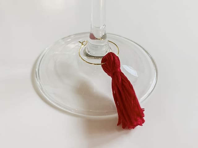 Red tassel charm on wine glass stem.